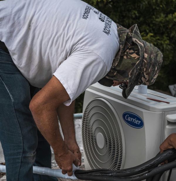 A man installing an air conditioner outside.