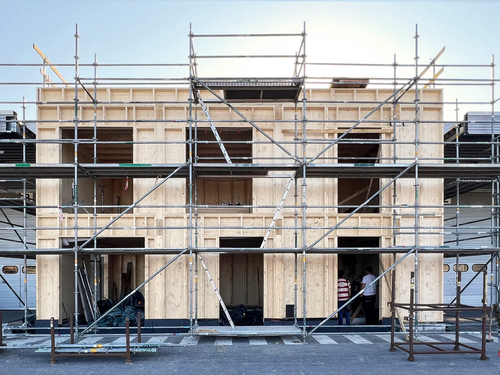 Robotically prefabricated timber building under construction with scaffolding, showing mass timber wall panels and structural components