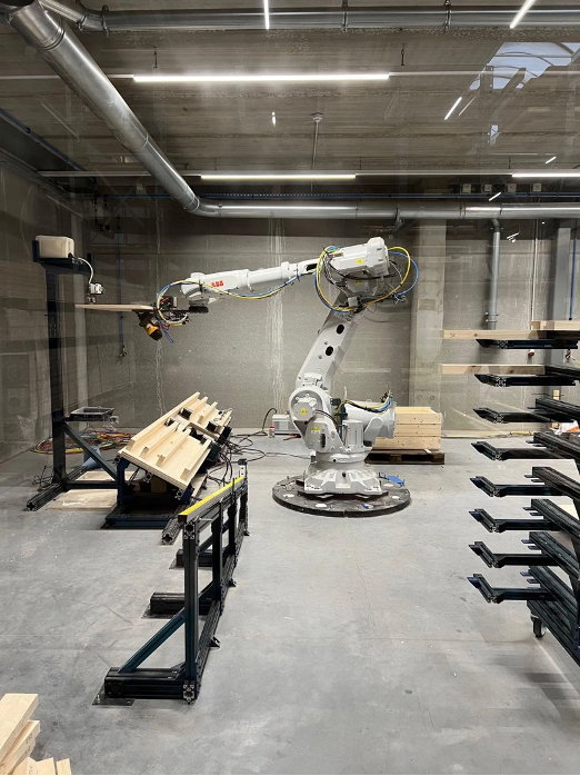 Industrial robotic arm fabricating timber wall panels inside a deployable construction microfactory