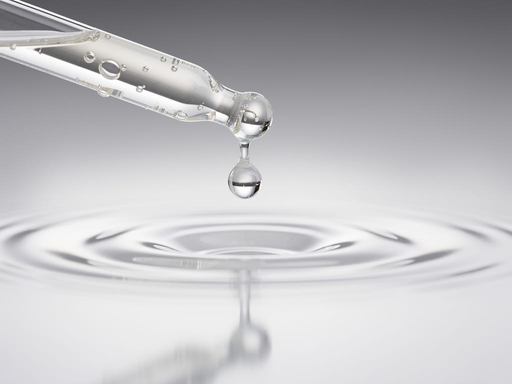 Close-up of a clear skincare serum drop from a dropper