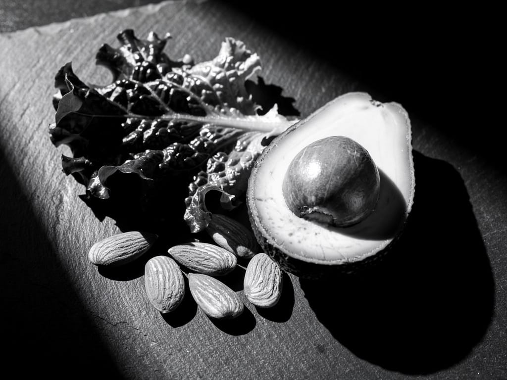 A collection of magnesium-rich foods like spinach, almonds, and avocado