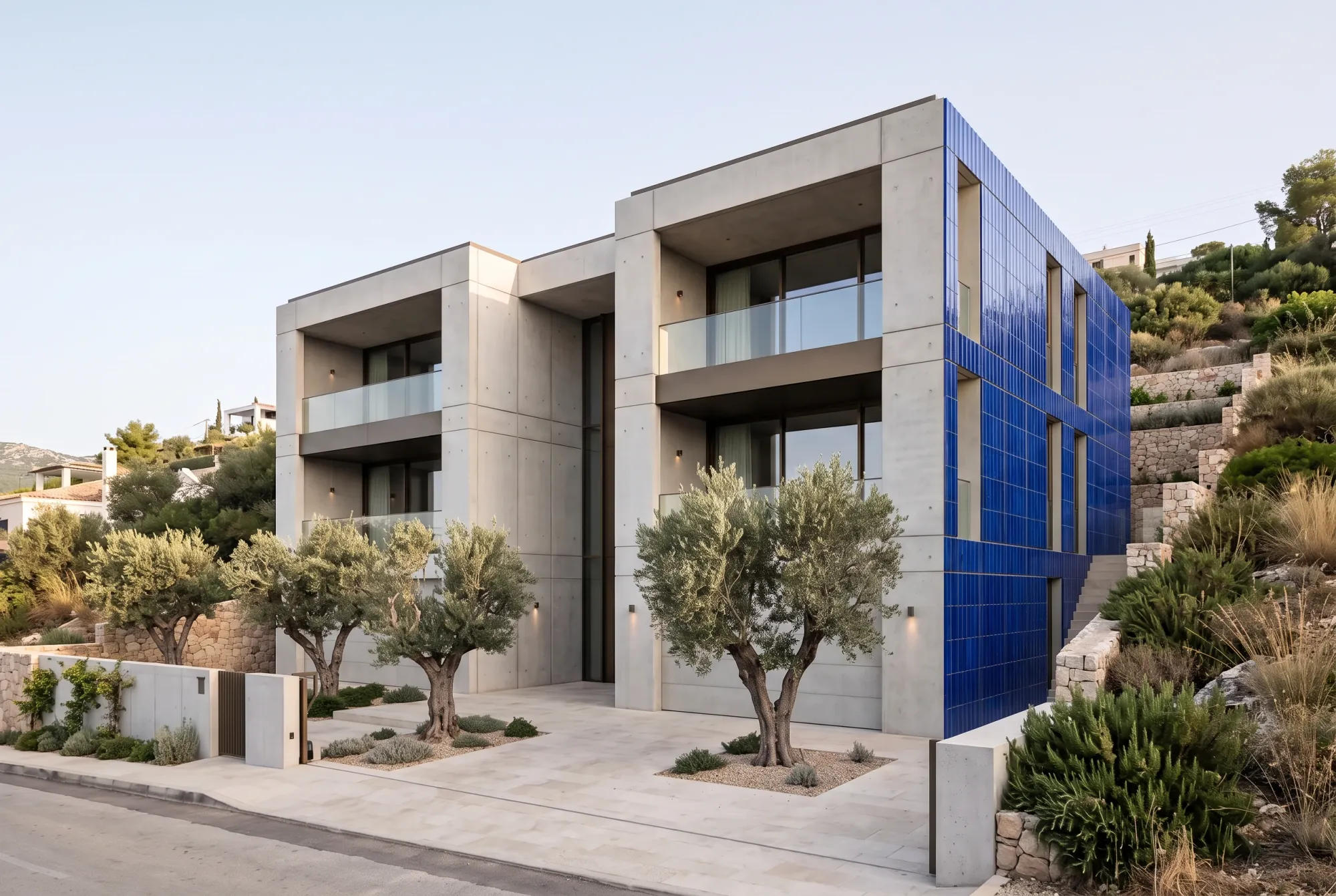 The marked side wall receives the ceramic ribs and blue colour while the front elevation remains pale concrete.