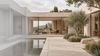 Courtyard architecture transitioning from a gray model-style view to limestone finishes, a furnished interior and planted landscape.