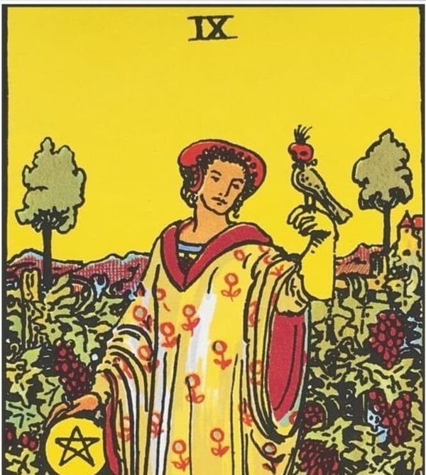 A figure stands in a lush garden with a bird perched on one hand and the other resting on a pentacle (coin).