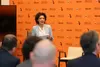 Una relatrice professionista parla con coinvolgimento durante un panel al Festival dell'Economia, sul palco con un microfono ad archetto, davanti a un fondale che riporta il logo dell'evento.