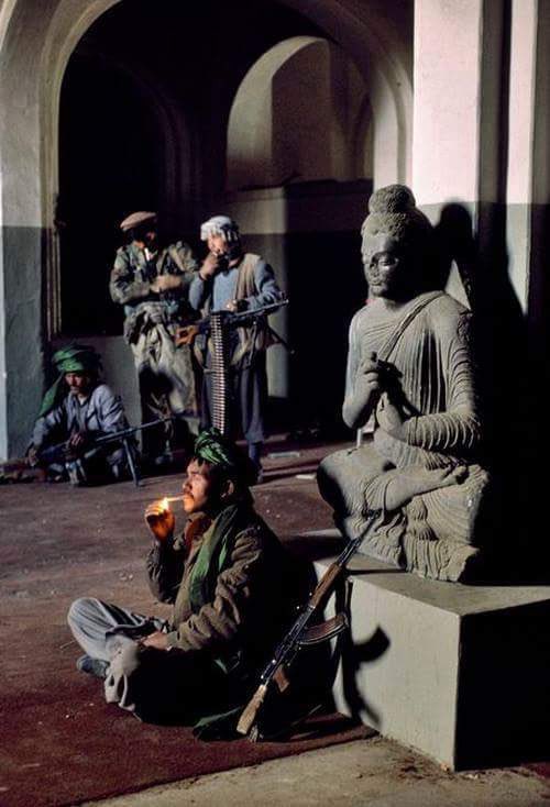 Taliban terrorists surrounding a Buddha statue