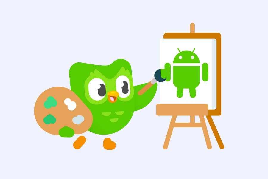 Duo holds a paint palette with one hand and paints a green android on a canvas with the other