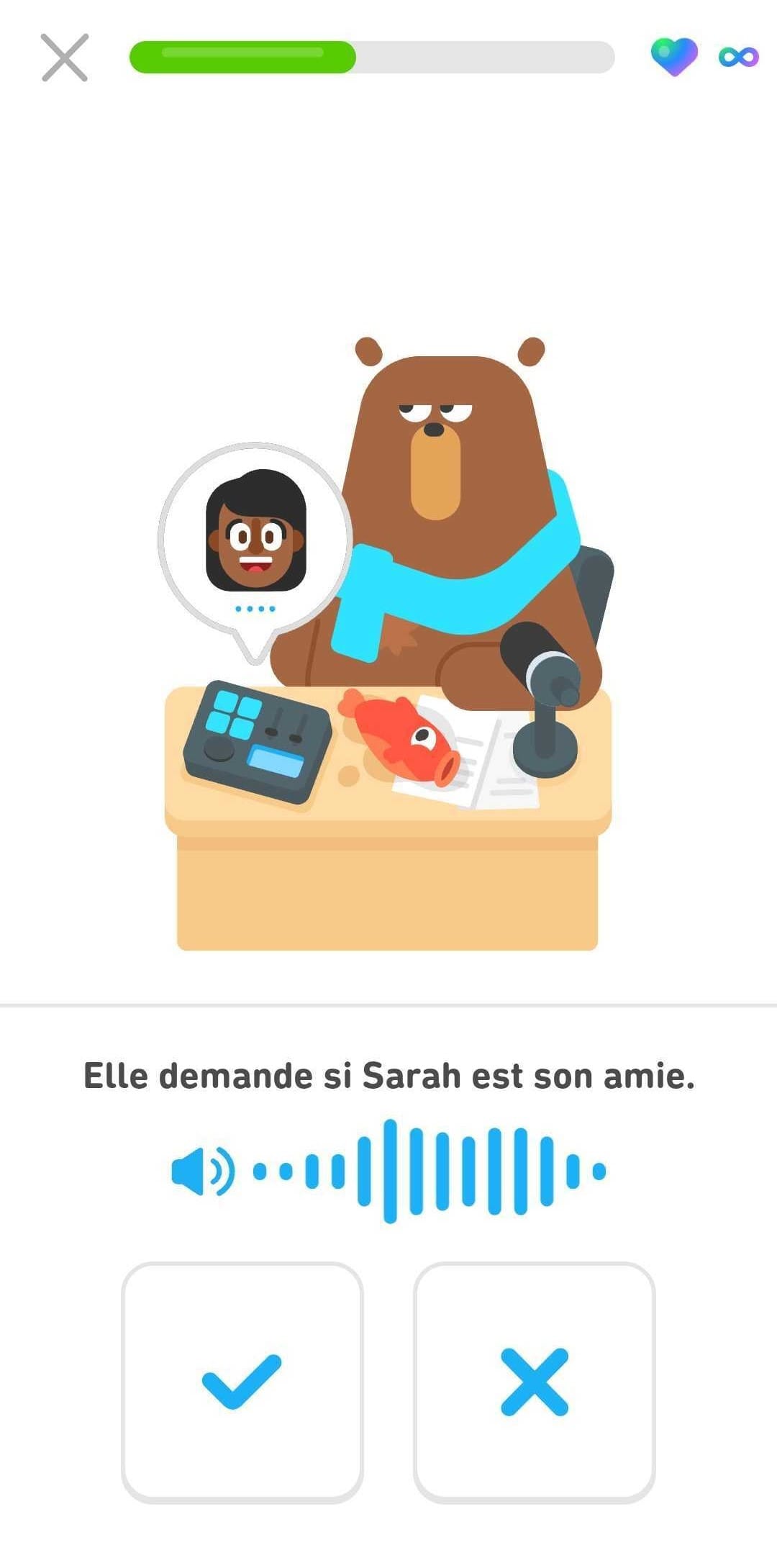 Capture d’écran d’un épisode DuoRadio. L’ours Falstaff est assis à son bureau, devant un micro et un enregistreur audio. Le visage d’une femme apparaît dans une bulle au-dessus de l’enregistreur audio. En bas de l’image, la phrase « Elle demande si Sarah est son amie. » L’utilisateur doit appuyer sur l’une des deux icônes pour dire si l’affirmation est vraie ou fausse.