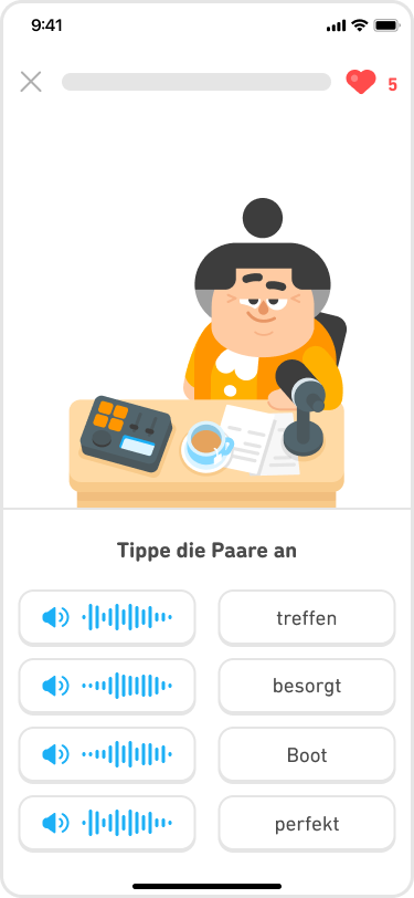  Screenshot einer Abbildung von Lucy, die hinter einem Mikrofon am Schreibtisch sitzt. Die Anweisung lautet: „Tippe die Paare an“. Darunter befinden sich vier blaue Lautsprecher-Schaltflächen mit Audiodateien und vier deutschen Wörtern, die jeweils einer Audiodatei zuzuordnen sind.