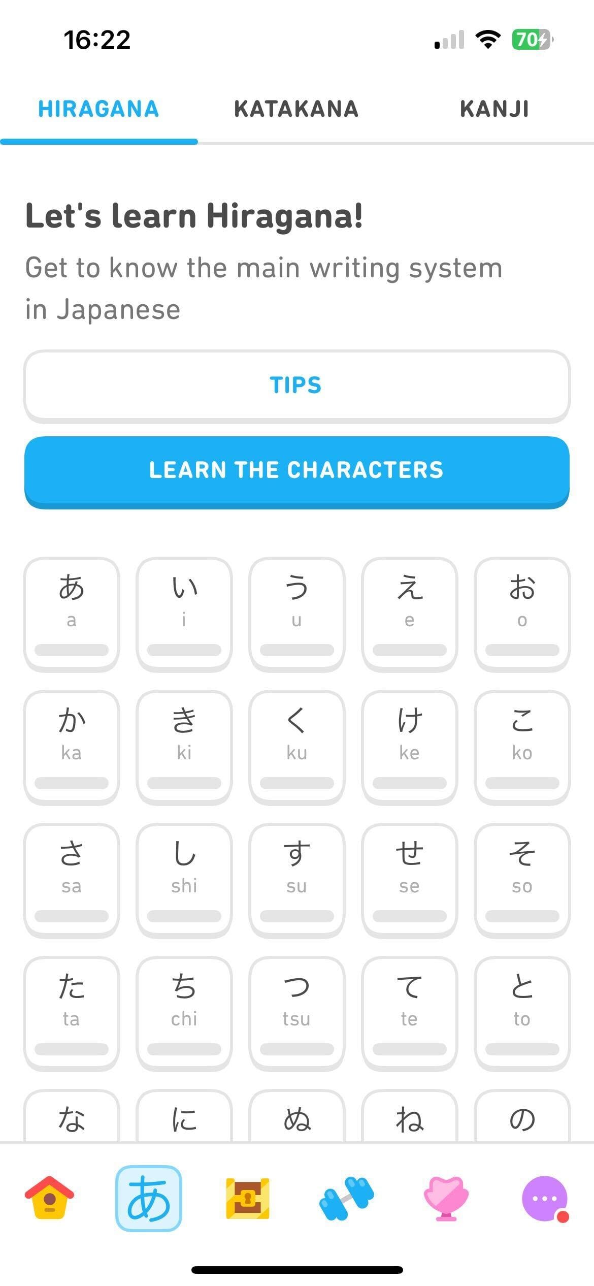 Captura de tela da aba de prática dos sistemas de escrita no curso de japonês para falantes de inglês. Na parte de cima, há o texto “Vamos aprender hiragana! Conheça o principal sistema de escrita japonês”. Em seguida, há o botão “Dicas” e o botão “Aprender os caracteres”. A maior parte da tela mostra uma tabela de 4 linhas e 5 colunas, na qual há blocos com diferentes caracteres do hiragana e letras do alfabeto latino representando o som de cada um. Mais blocos vão aparecer se a tela for rolada para baixo.
