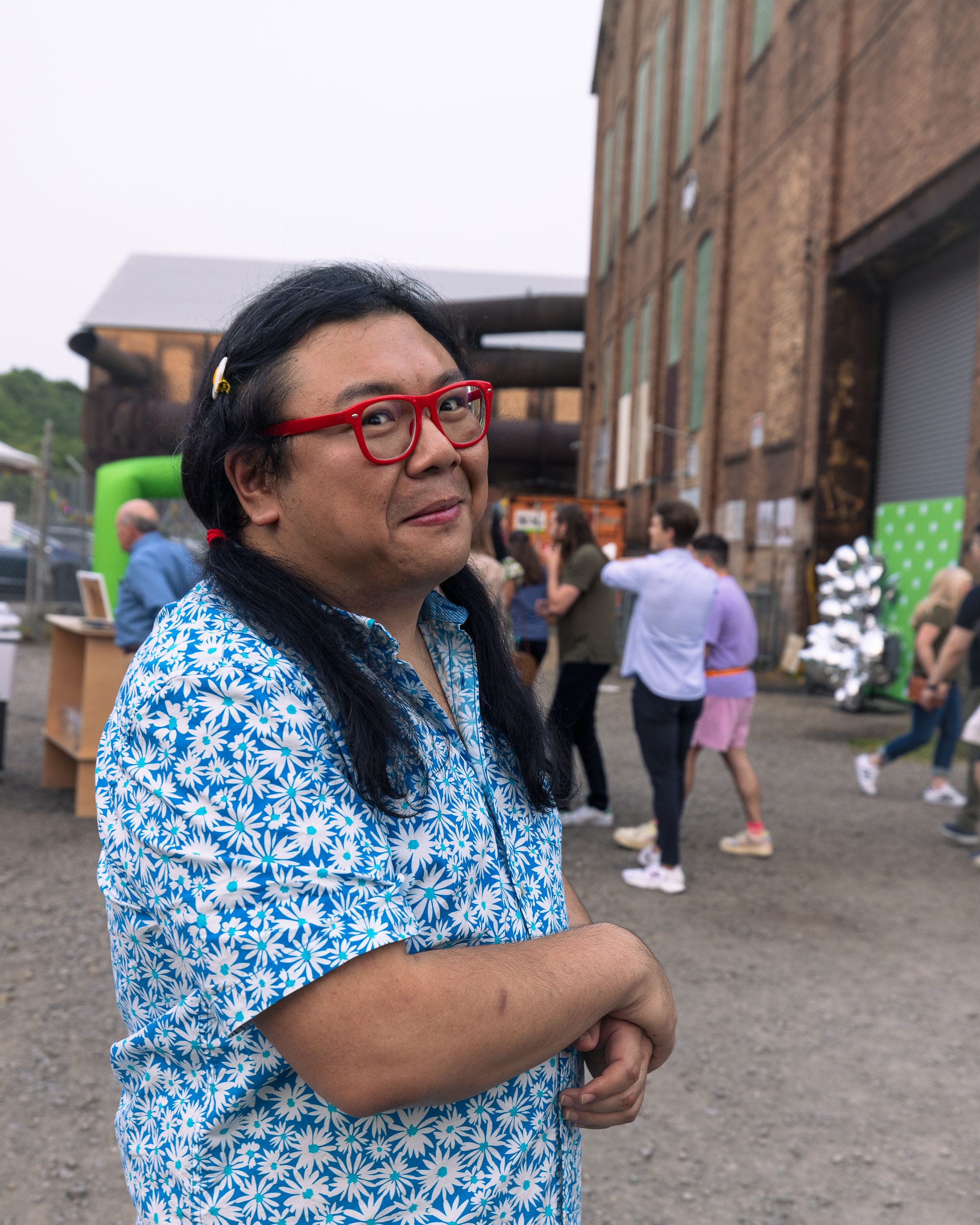 Foto de Duo com um sorrisinho em frente a um prédio e uma multidão de pessoas