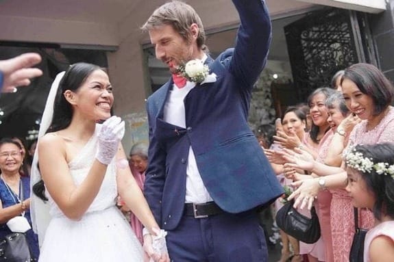 Rob, no seu terno de noivo, e Amanda, de vestido de noiva, riem e sorriem para a câmera.