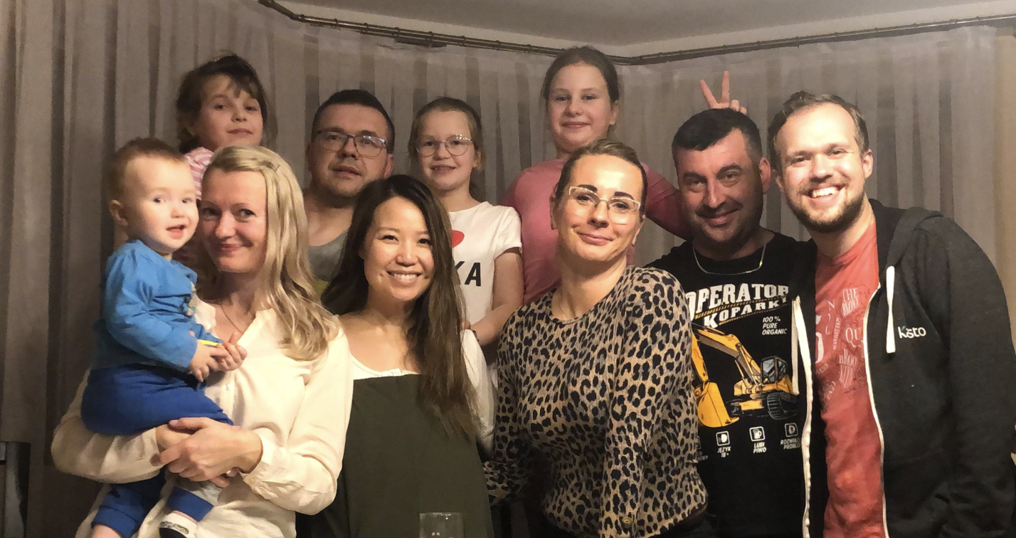 Me with my cousins Michał and Grzesiek, standing next to their wives and children, all smiling and posing for the camera, inside Grzesiek’s home. Grzesiek’s daughter is giving him bunny ears.