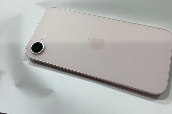 櫻花粉色的 iPhone 17e 背面，放在白色桌面上