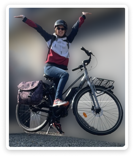 A picture of me on my electric bike, with my arms up in the air in a victory pose.