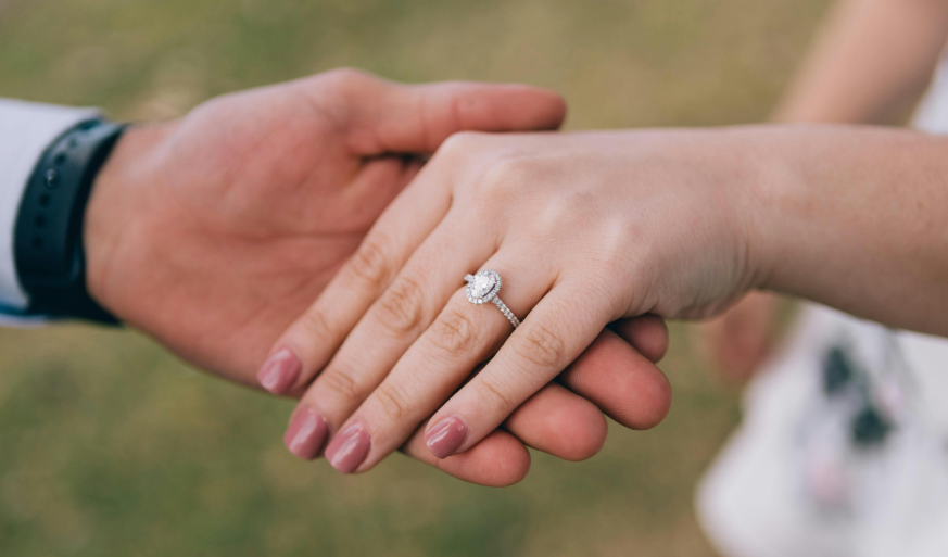 A woman wearing a ring holds hands with a man
