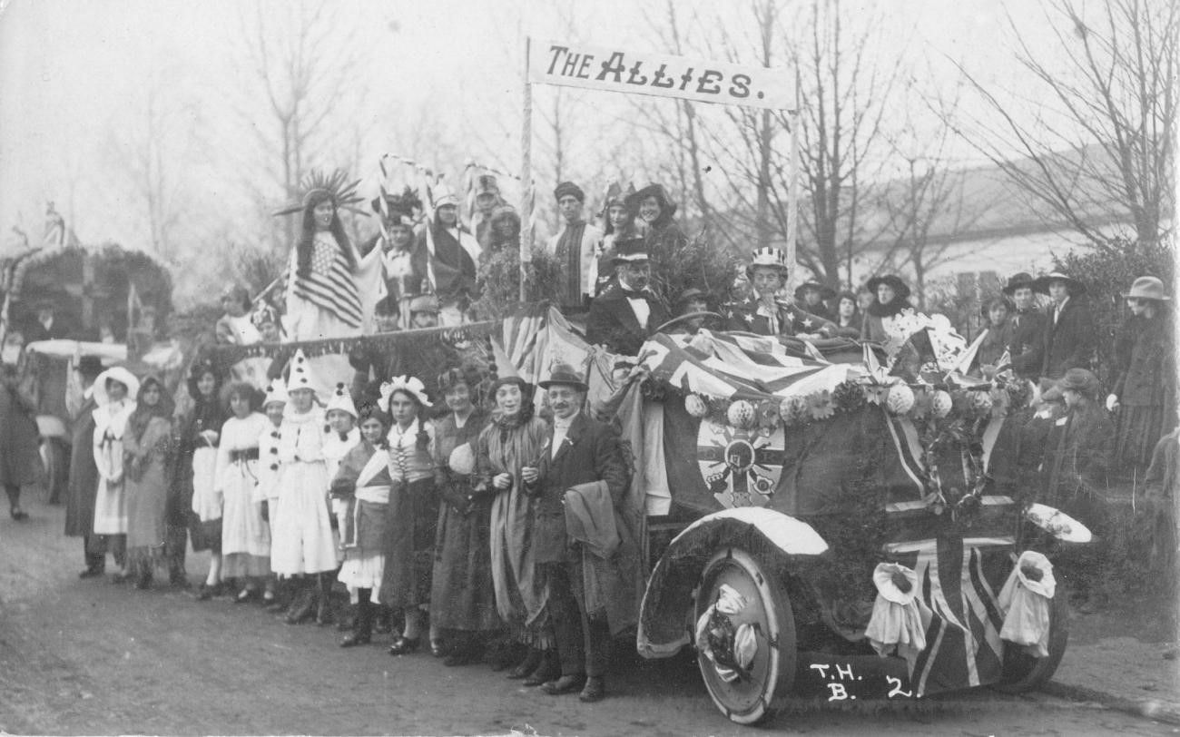 A group of people standing around a car with a flag on it
Description automatically generated with low confidence
