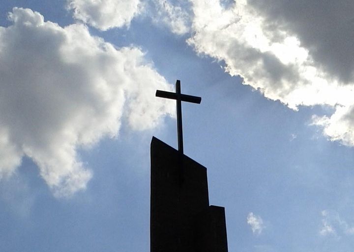 Photo of a modern steeple topped with a cross against a background of sky and clouds. Original at https://morguefile.com/p/1137637