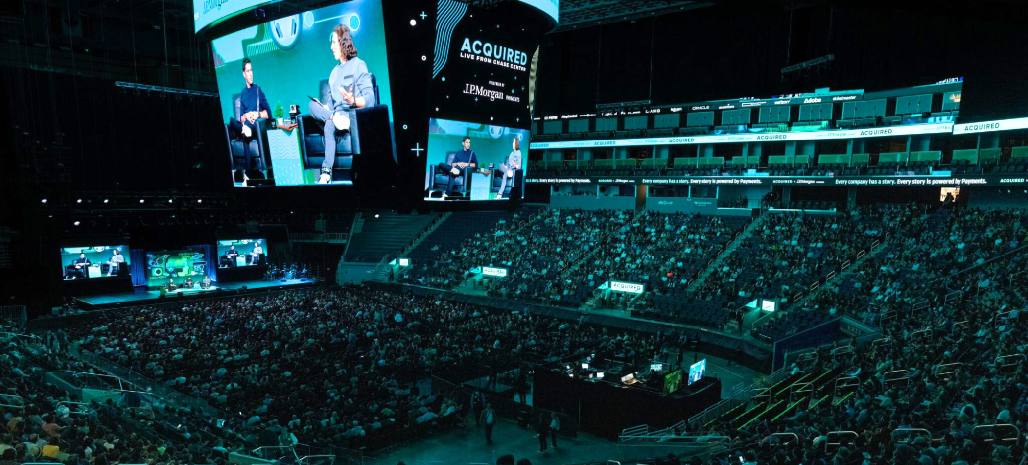 Photo of a live Acquired podcast recording in a packed stadium