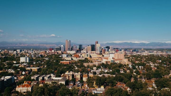 Aerial view of the Denver skyline with the Front Range behind it and residential neighborhoods in front