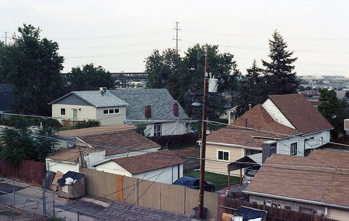 Rooftops of an older single-family neighborhood with mature trees and power lines