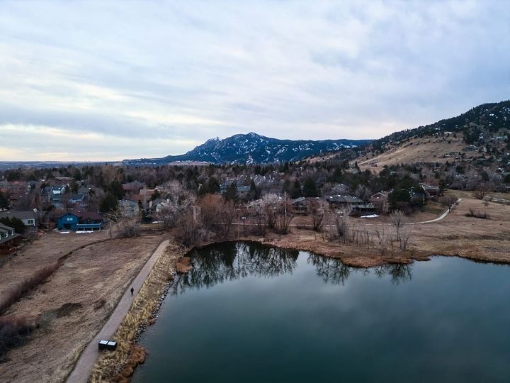 Boulder homes spread below the snow-dusted foothills, seen from above Wonderland Lake in winter