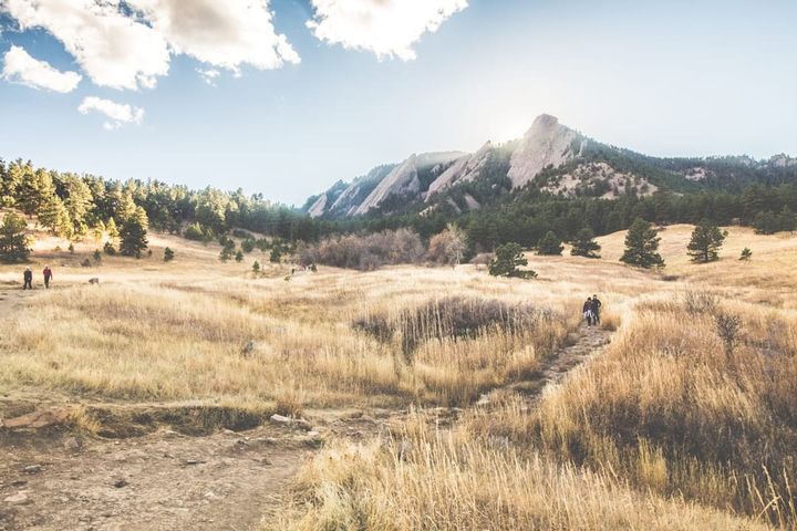 The Flatirons above a golden open-space meadow and hiking trail in south Boulder, Colorado