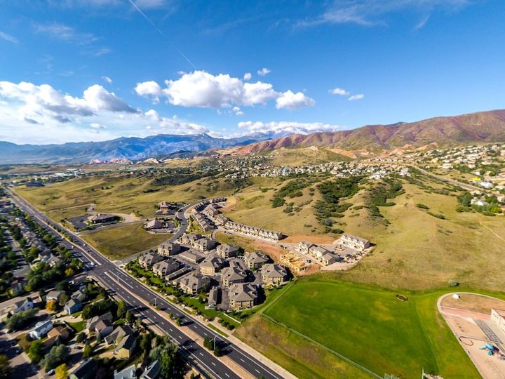 A two-story single-family home with a covered front porch and the Front Range foothills behind it