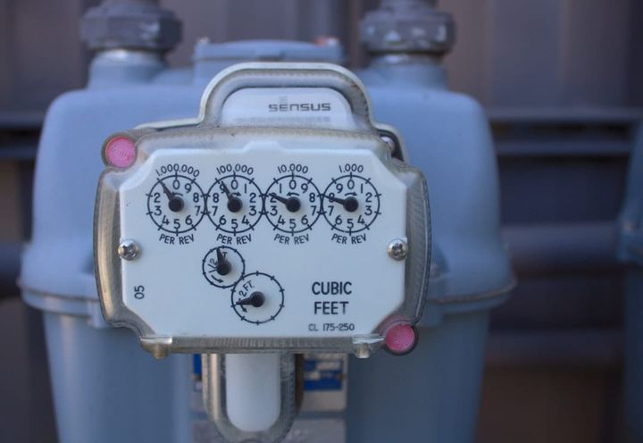 Close-up of a gas meter face with four numbered counting dials and the words CUBIC FEET.