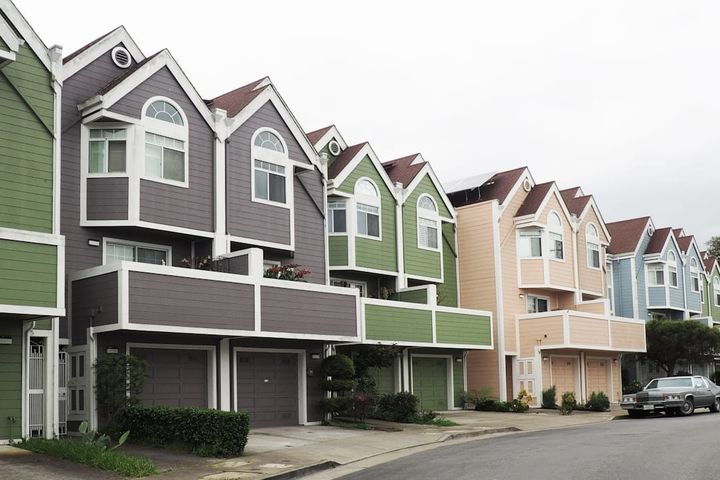 A row of newer multi-story townhomes with garages along a planned-subdivision street