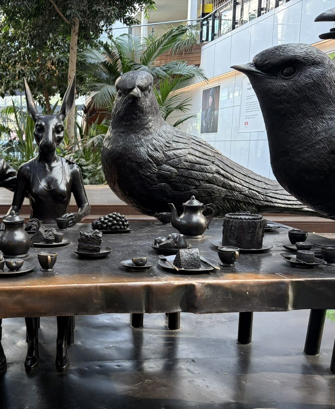 Life-sized bronze sculptures of birds and animals seated around a long table set with a bronze tea service.