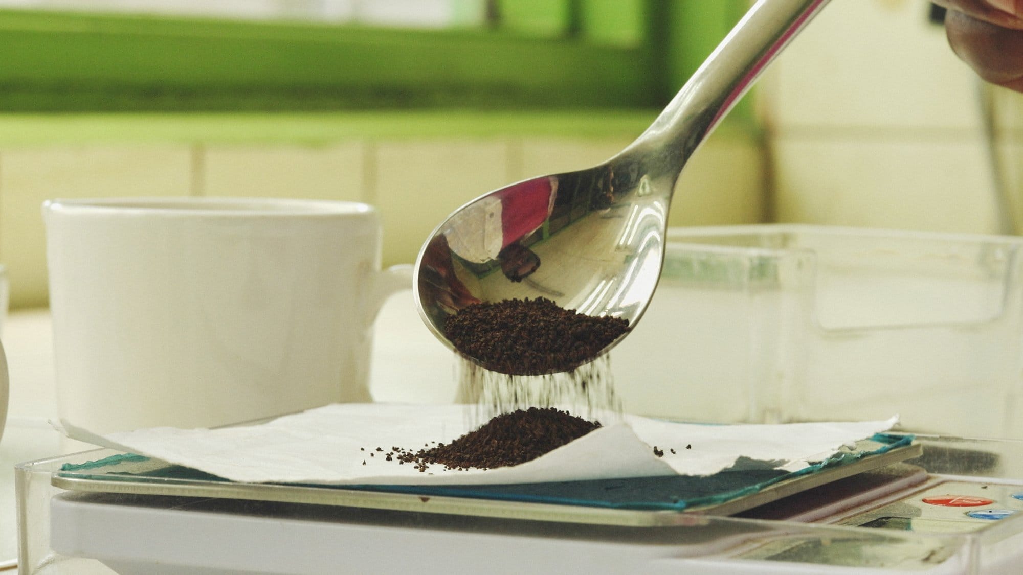 Spoon of dry tea leaves over a tasting scale