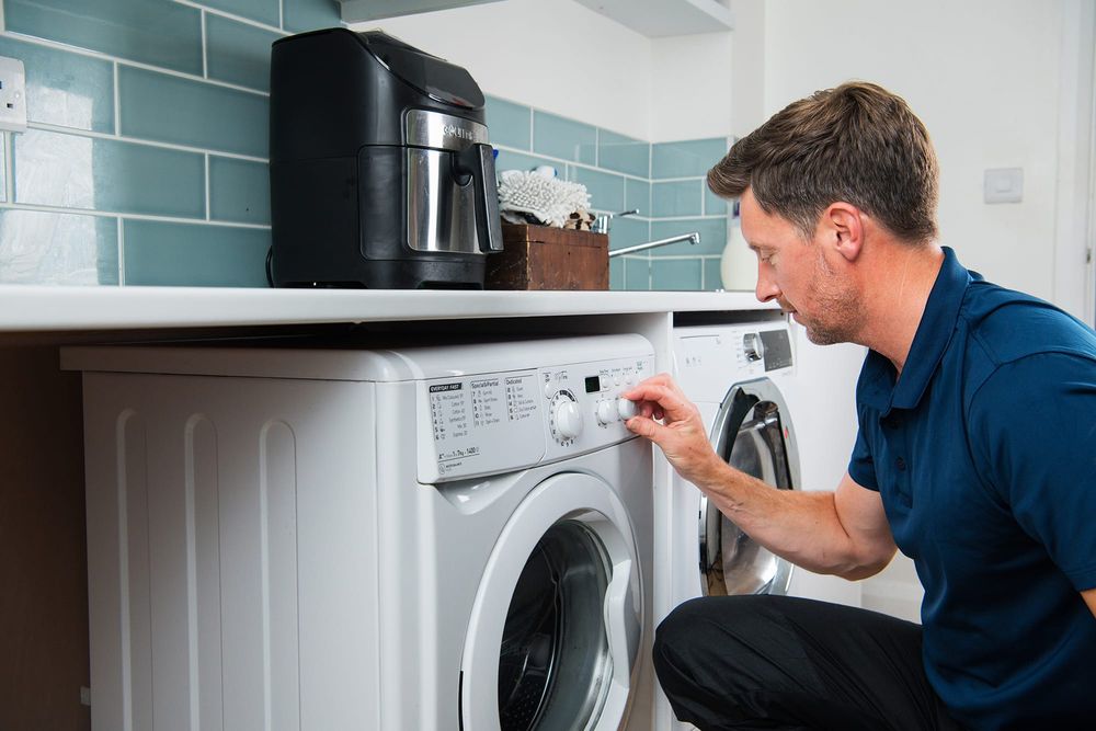 Domestic & General engineer adjusting the settings on a washing machine