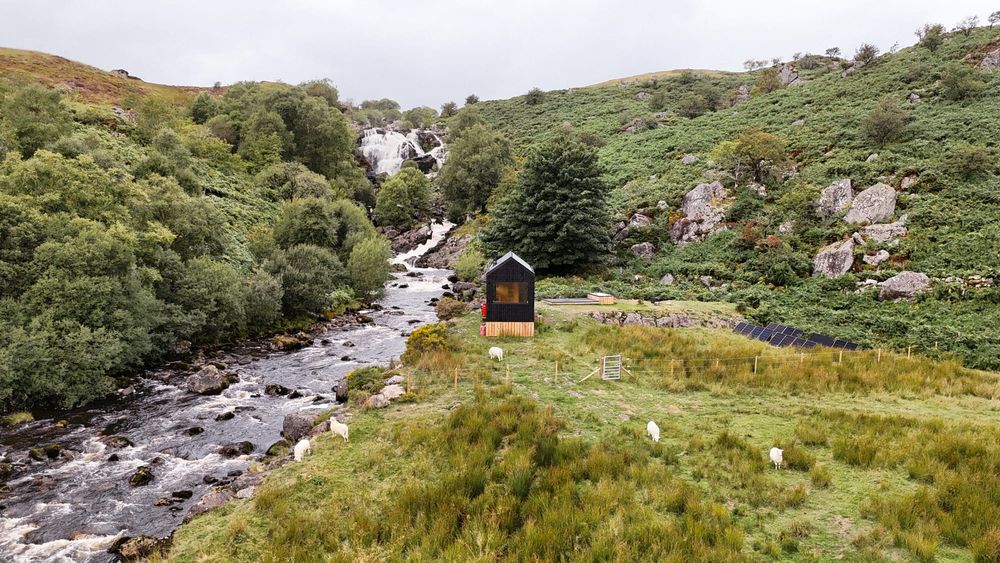 Shacks off-grid cabin beside a waterfall in the UK countryside