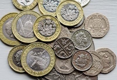 a pile of british coins sitting on top of a table
