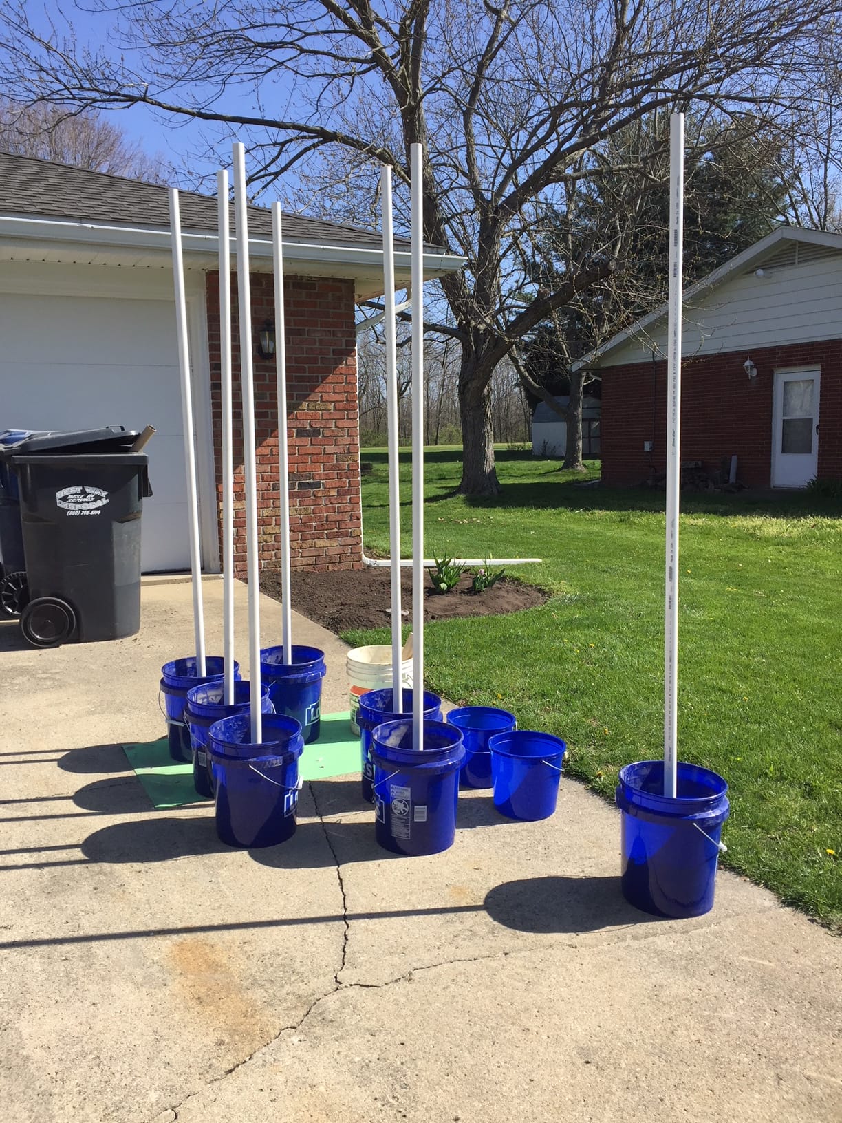 five gallon buckets with PVC pipes sticking straight up out of them, anchored by concrete