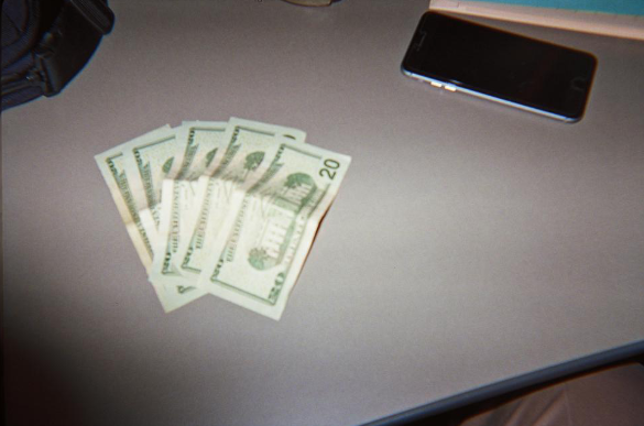 five twenty dollar bills and a smart phone on a table