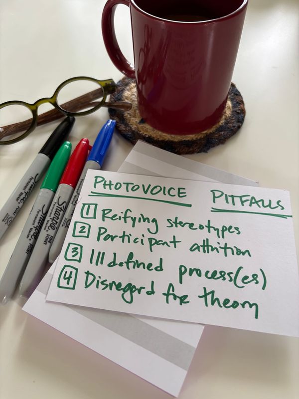 index card on a white table surrounded by pens, glasses, and a coffee cup; the card contains a handwritten list of the four pitfalls outlined in the post