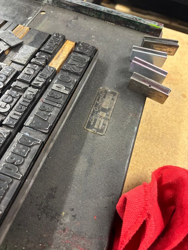 letterpress type and magnets on a Line-O-Scribe press with a red cloth beside it