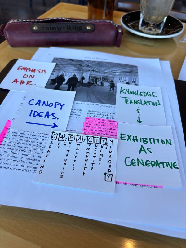 five half index cards with the four notes written on them sitting atop a highlighted page of the featured journal article