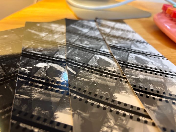 black and white film printed test strips on a table with a keyboard and monitor partially viewable in the background