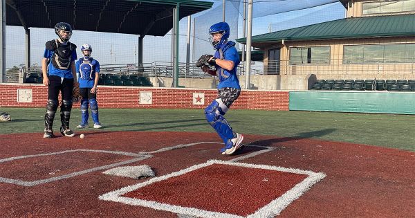 Three catchers in full gear training at Premier Baseball of Texas, with one preparing to throw during a Tomball Kings camp.