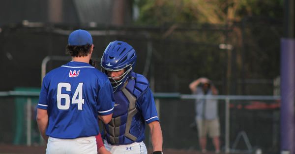 Pitcher and catcher deep in conversation on the mound, strategizing during a game—capturing the trust and unity built through seasons of playing together.