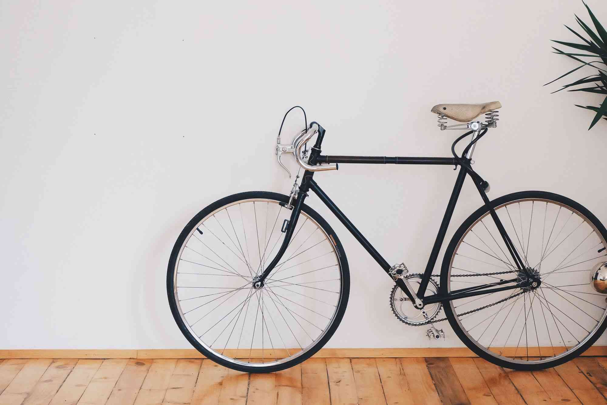Black-Framed-Bike-On-Wood-Panelled-Floor-With-White-Wall-Backdrop