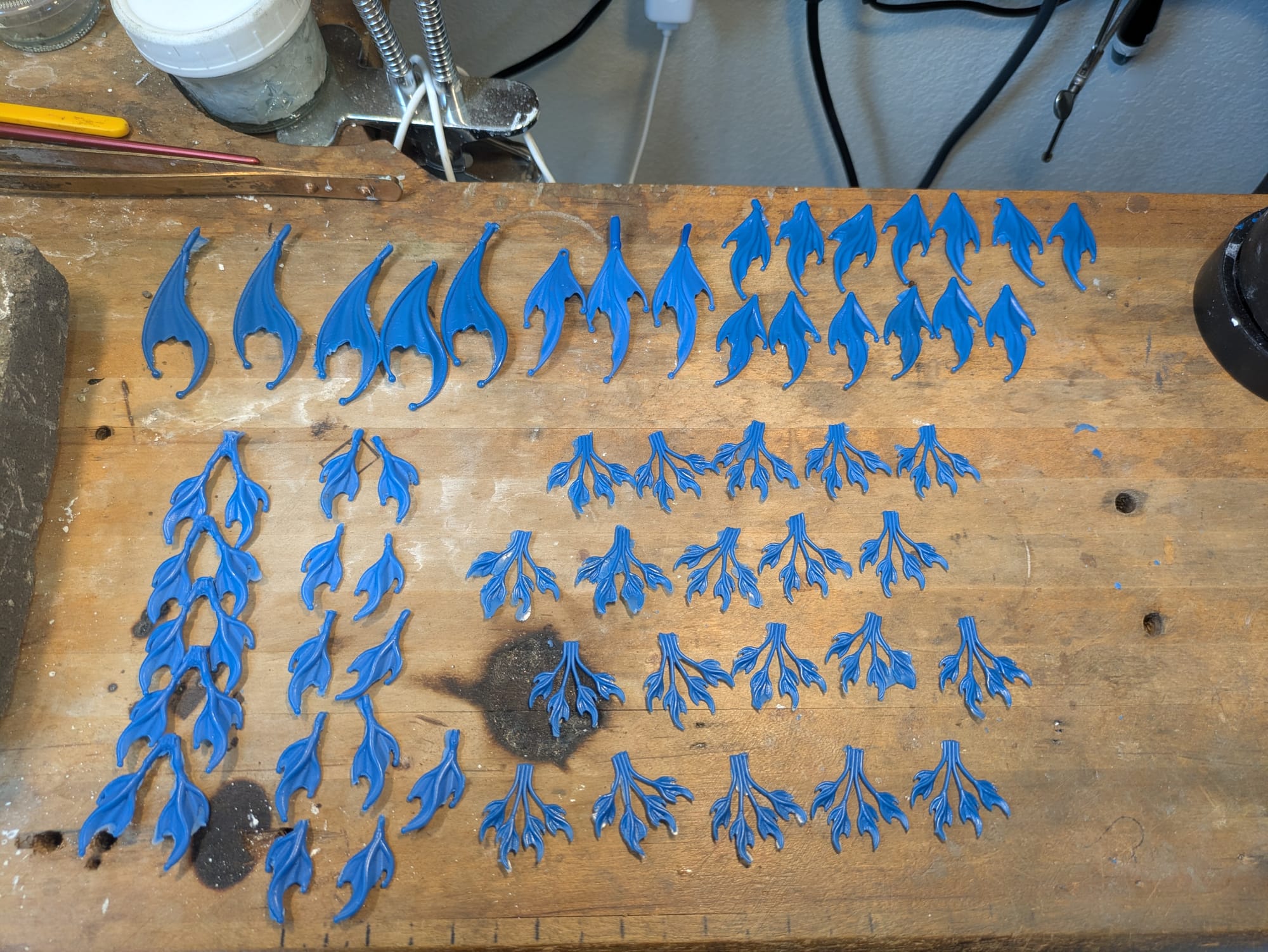 Quite a lot of wax models spread out on a desk top, some still have the stems from the molds attached.