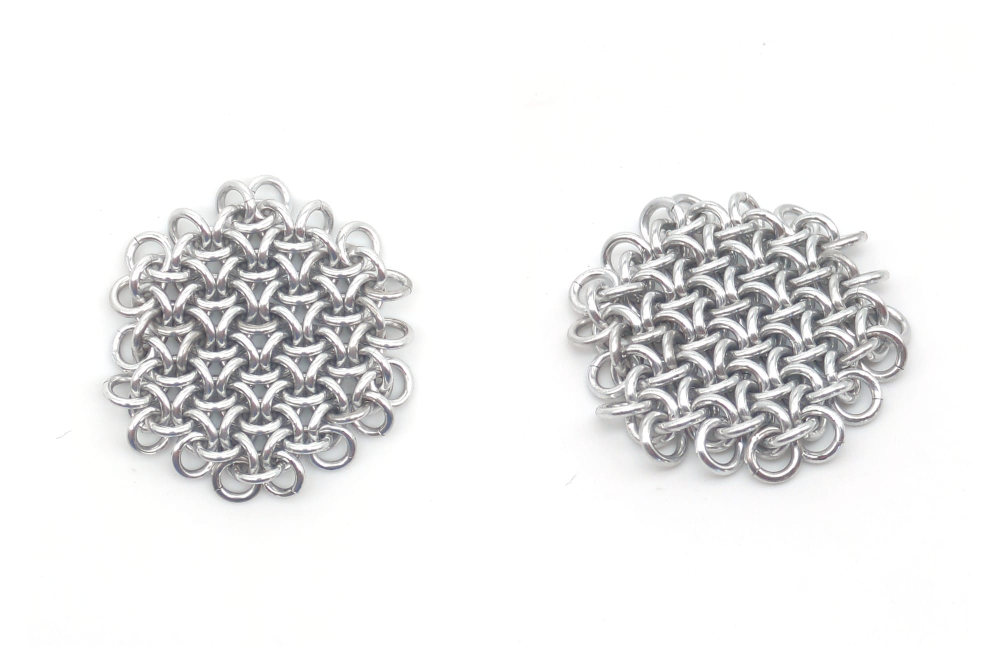Two views of a key-chain-sized patch of chainmail. It has the hexagonal structure of honeycomb, but is made of smooth round rings.