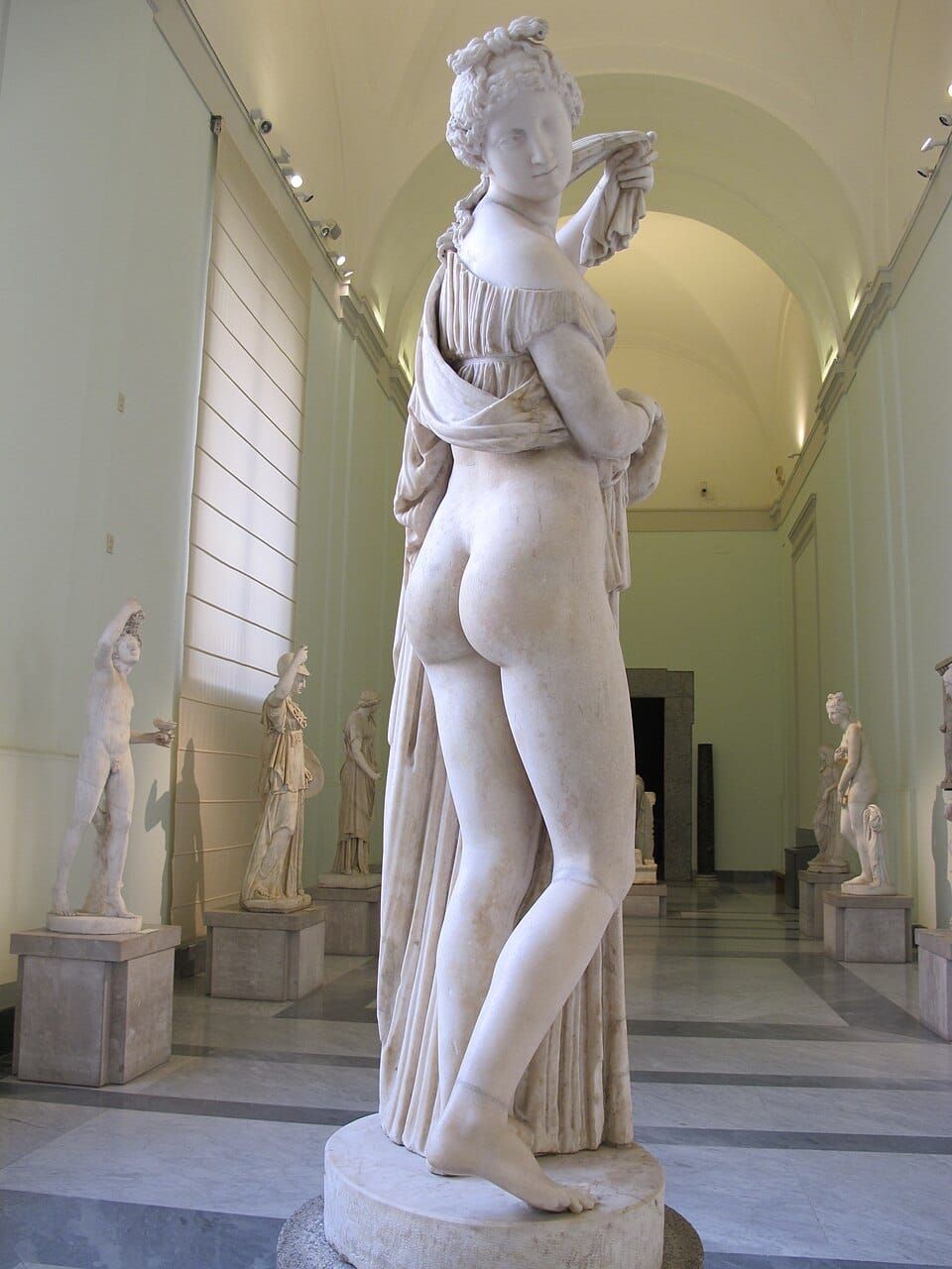 white marble statue of Venus lifting her skirt and displaying her butt