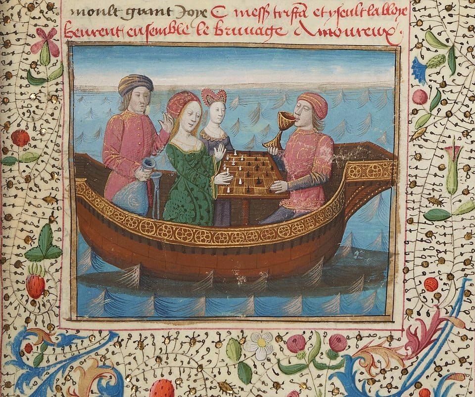 Illuminated manuscript illustration of Tristan and Isolde playing chess on a boat. Tristan is drinking from a goblet. The painting is surrounded by delicately drawn flowering vines.