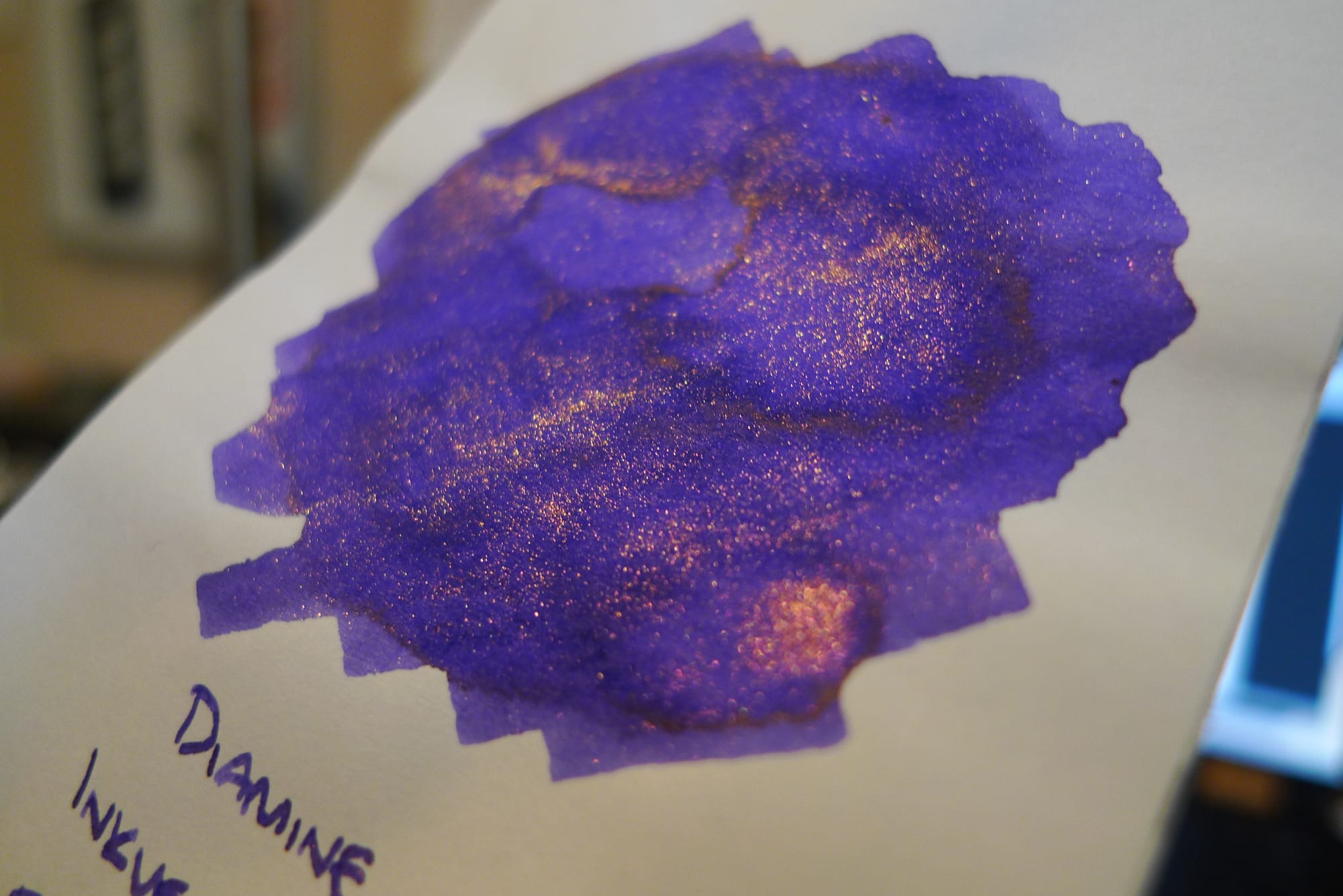 Angled close-up of purple ink swatch showing the bronzey rose shimmer on top of the swatch
