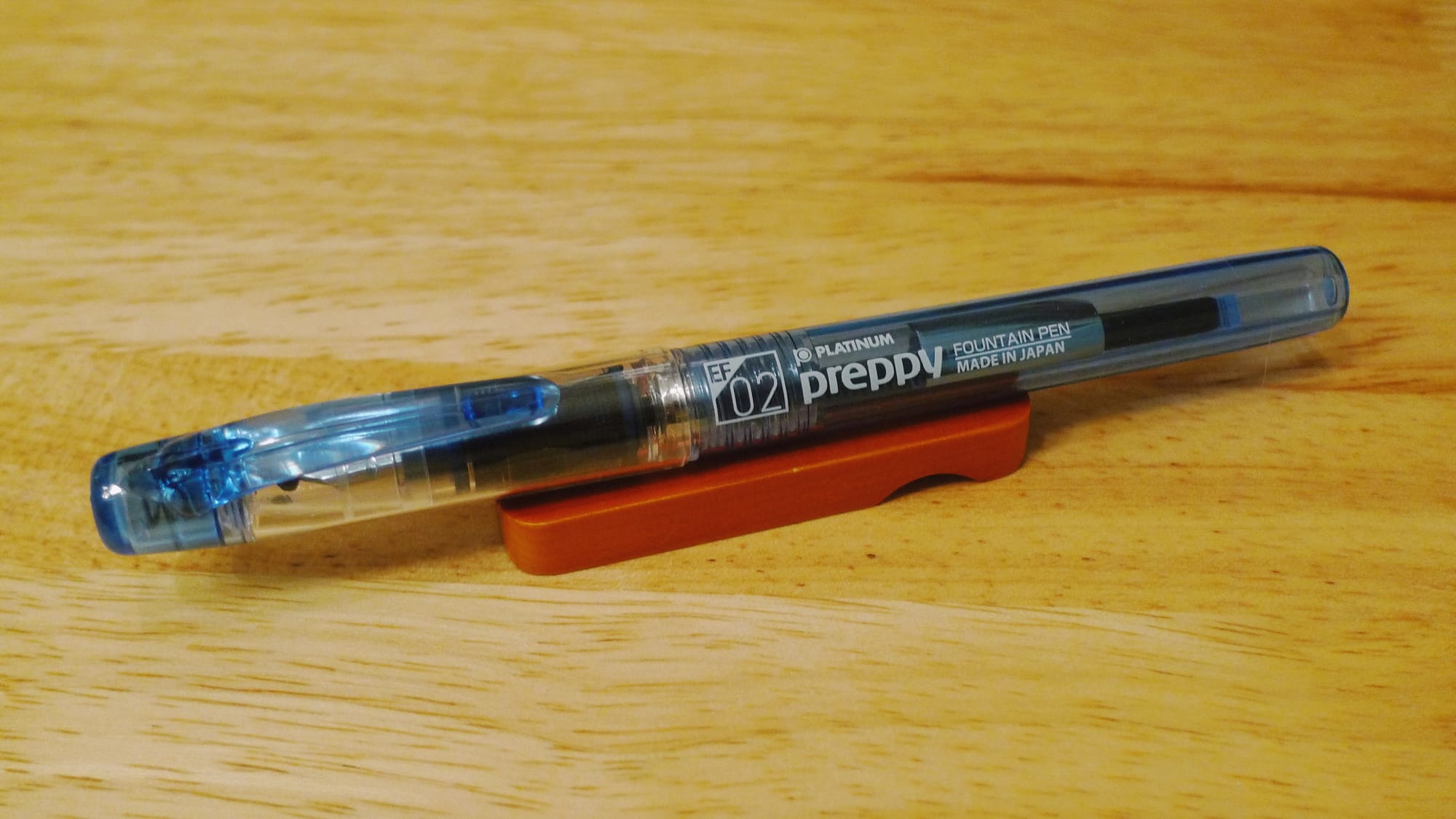 Plastic fountain pen with a clear cap and translucent blue body and clip, labeled "EF 02" to indicate an extra fine nib
